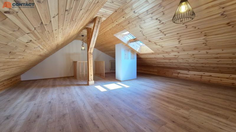 Attic room with wooden paneling and wood-patterned flooring.