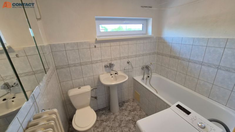 Bathroom in a 2-room apartment with a bathtub, sink, washing machine, and tiled walls.