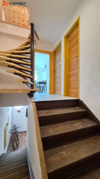 A staircase with a wooden railing leading to a 2-room apartment with a view of the entrance door.