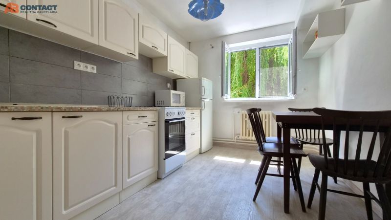 A kitchen with white cabinets and a dining table in a 2-room apartment.