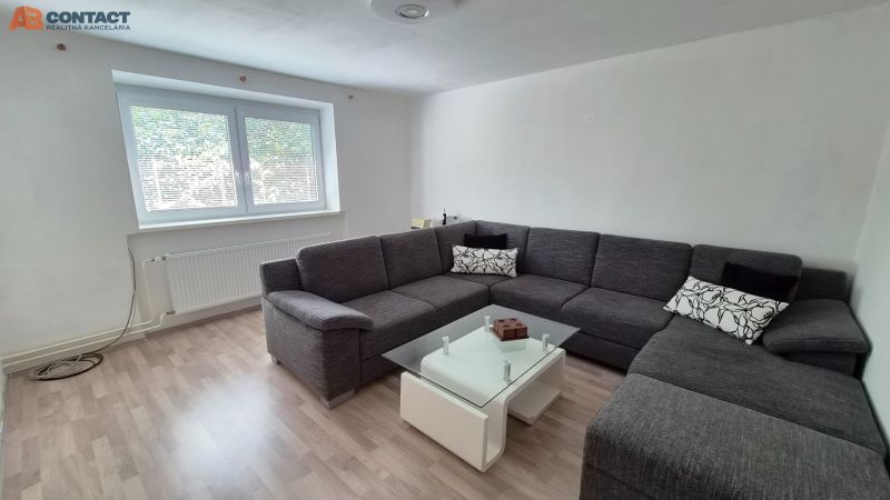 Living room with a gray corner sofa and a table, floor with wood decor.