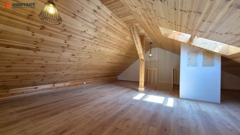 Attic room in a 2-room apartment with a wooden decor floor and wooden paneling.