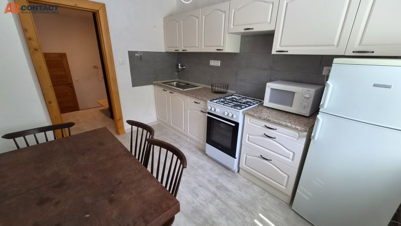 Kitchen in a 2-room apartment with a wooden table, microwave, and gas stove.