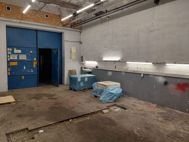 Warehouses and halls with blue doors, lighting, and materials on the floor with a wooden decor.