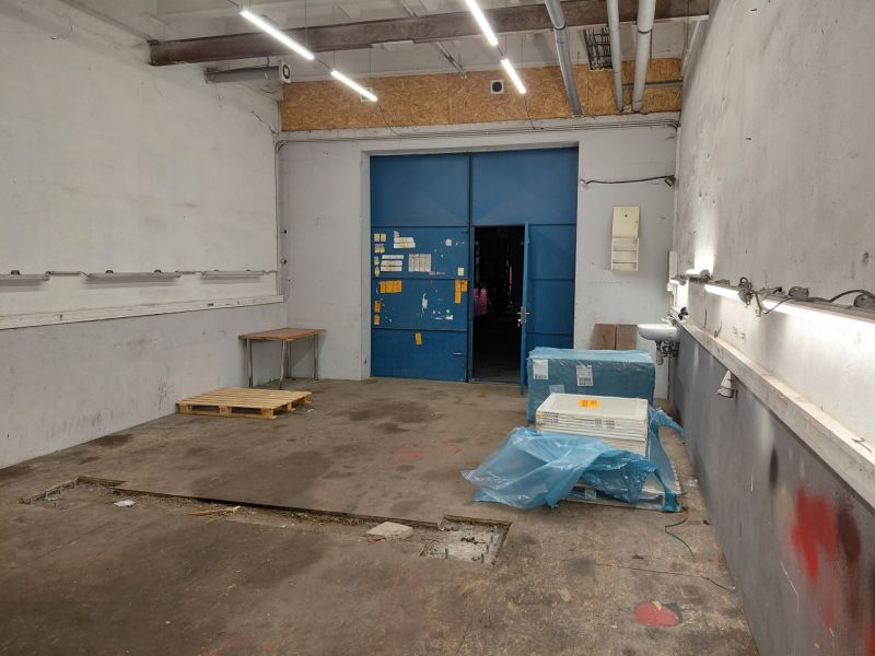 A view of a storage area with lighting, a pallet, and blue entrance doors.