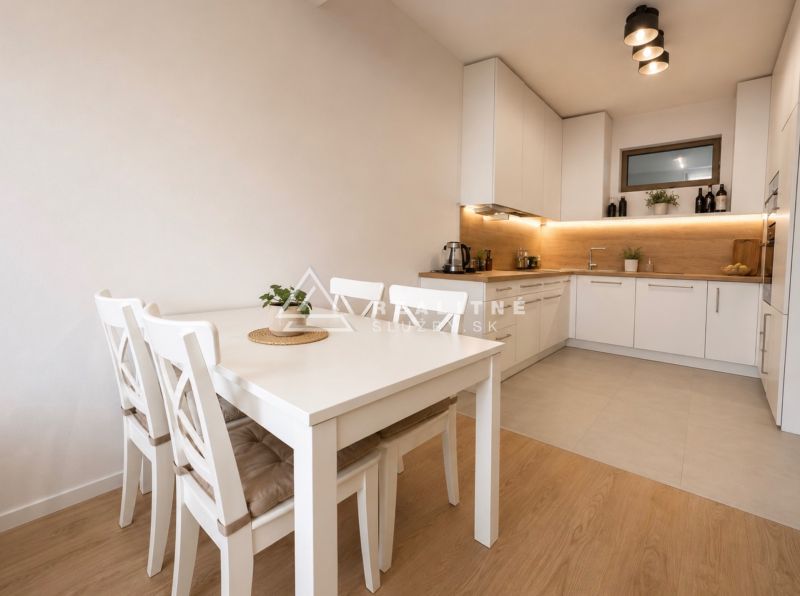 A kitchen in a 2-room apartment with a white table and a floor with a wooden decor.