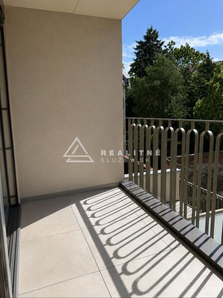 A balcony with a railing and a view of greenery in a 2-room apartment.
