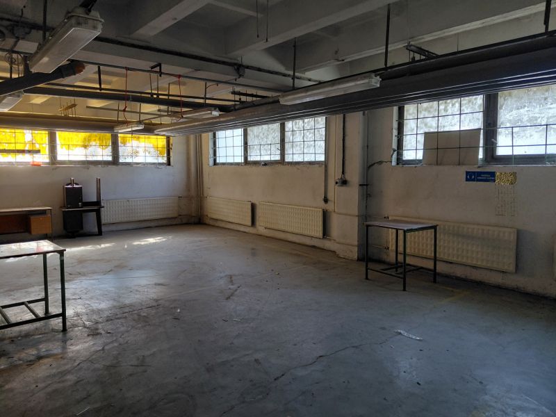 Warehouse space with concrete floor, windows, and old furniture. Warehouses and halls.