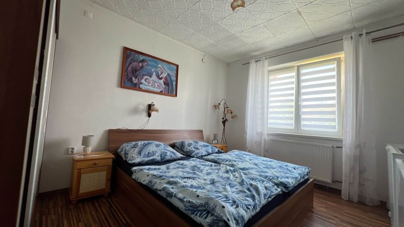 A bedroom in a 3-room apartment with a bed and a picture on the wall.