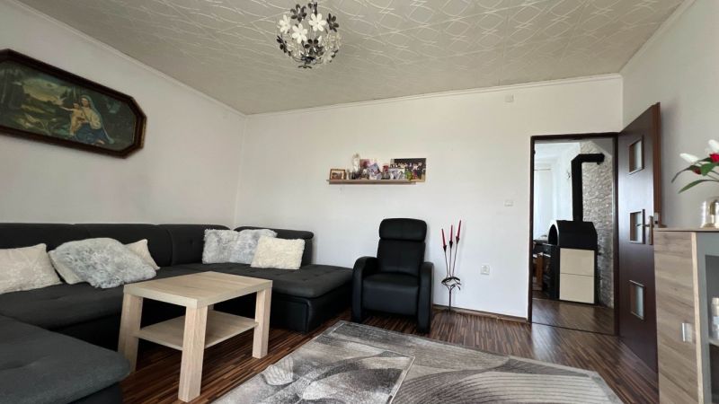Living room in a three-room apartment with a wooden decor floor, comfortable seating, and decorations.