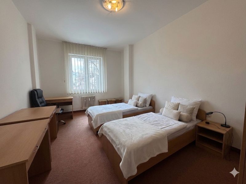 A bedroom in a 3-room apartment with separate beds and a work desk.