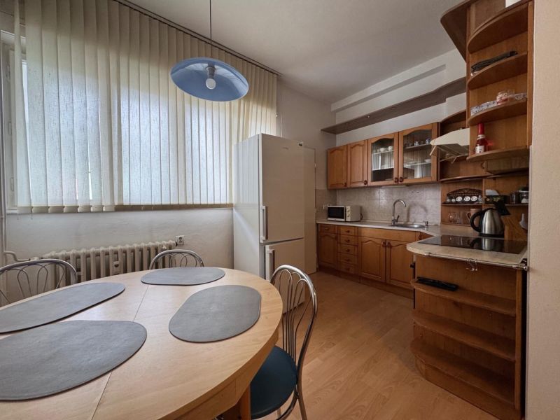 A kitchen in a 3-room apartment with a wooden decor floor and a dining table.