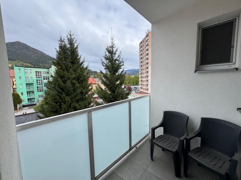 The balcony of a 3-room apartment in Ružomberok, with a view of greenery and surrounding buildings.