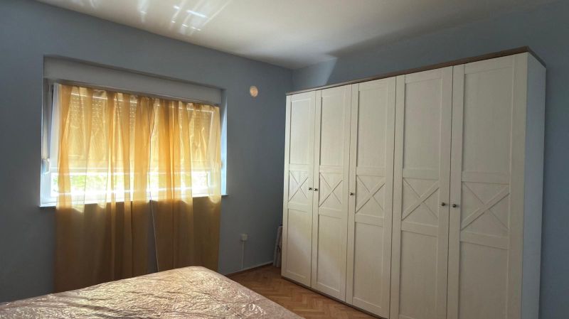 Bedroom in a family house with a white wardrobe and a wooden decor floor.