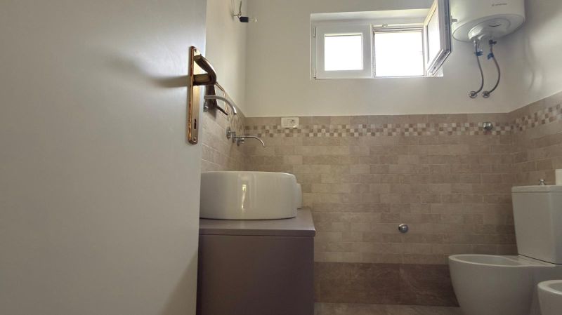 A bathroom in a family house with beige tiles and a modern sink.