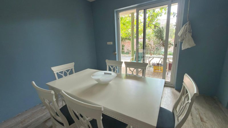 Dining area with a white table and chairs, wooden decor flooring, garden view.