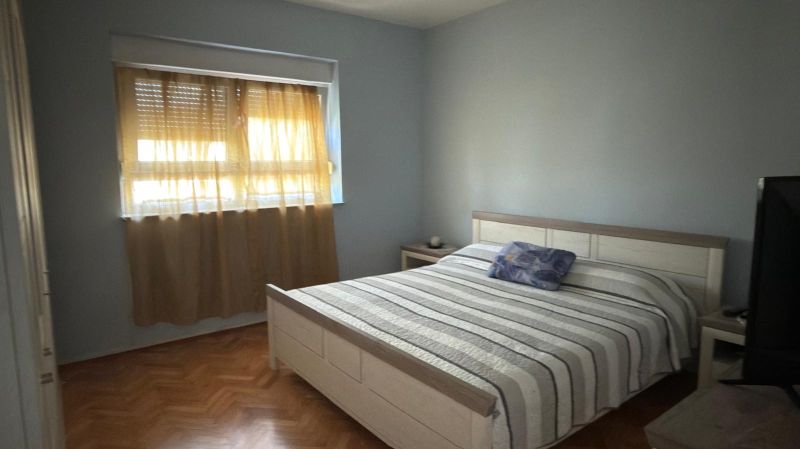 A bedroom in a family house with two windows and a wooden decor floor.