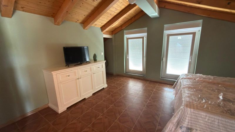 The attic in the family house contains a white dresser, a television, and skylights.