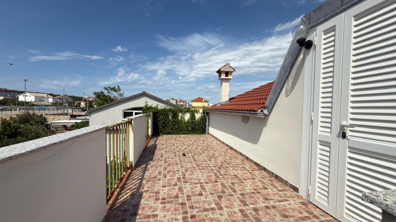 A terrace with a view of family houses in Ražanac, with tiles and white doors.