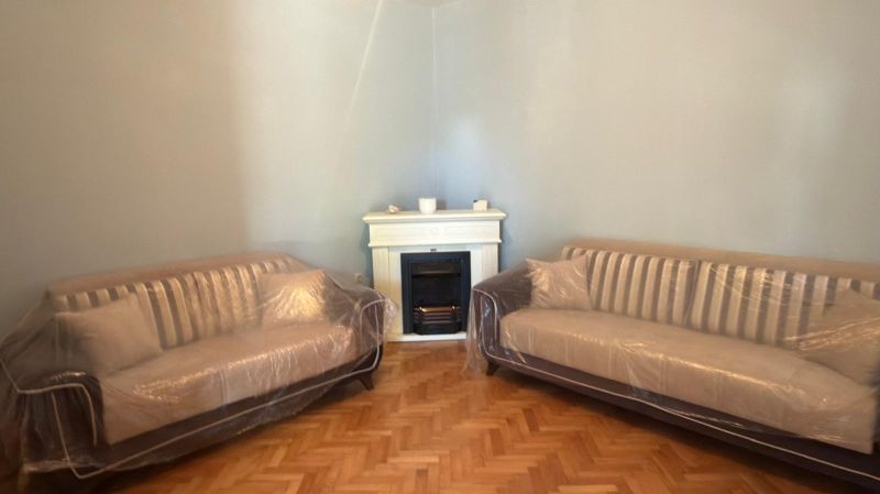 Two sofas with plastic upholstery and a fireplace in the background, floor with wooden decor.