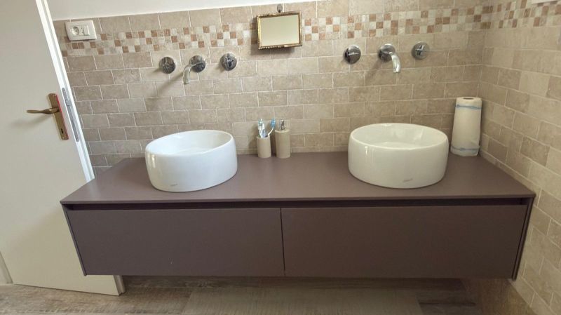 Double sinks on a dark countertop with tiles in a family house.