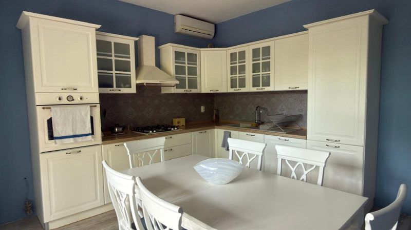A family house kitchen with a white kitchen unit, dining table, and chairs.
