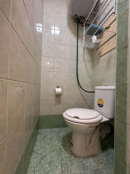Toilet in a holiday apartment with tiles up to half the wall, green tiles.