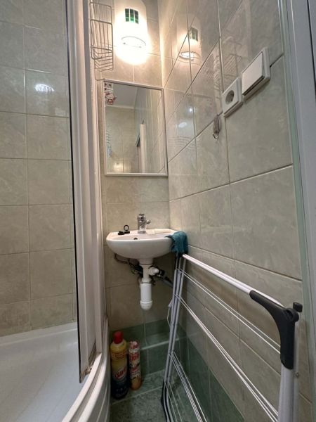 Bathroom of the recreational apartment with a sink, shower, and clothes dryer.