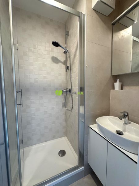Shower corner with ceramic tiles in the bathroom of a studio apartment.