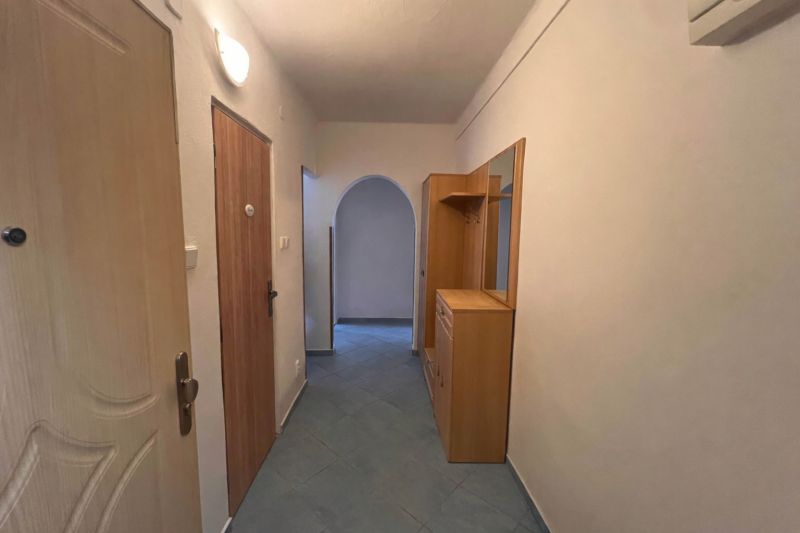 A hallway with tiles, built-in furniture, and an arched passageway in a 2-room apartment.