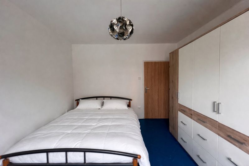 A bedroom in a two-room apartment with a bed, a wardrobe, and a blue floor.