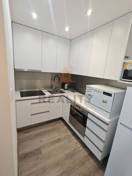 Kitchen unit in a one-room apartment with appliances and a wooden decor floor.