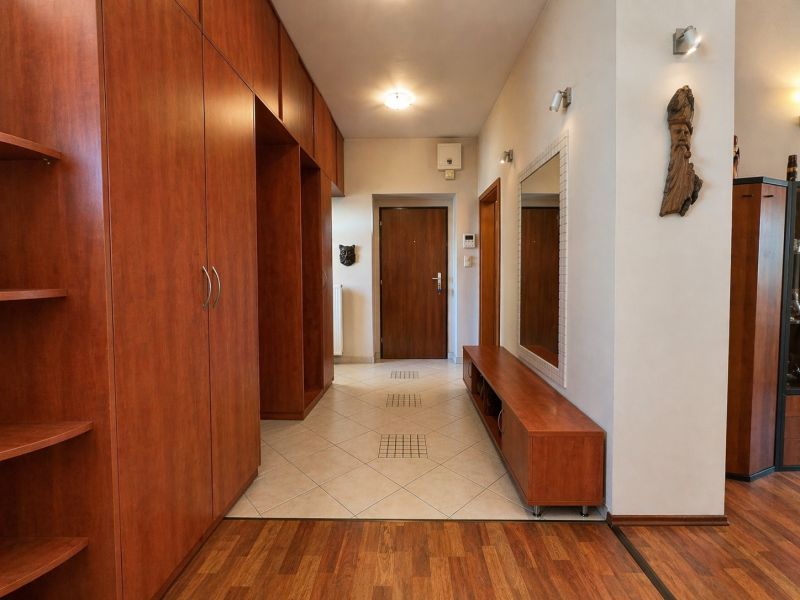 A spacious hallway with a wooden decor floor and a large mirrored wall in a 4-room apartment.