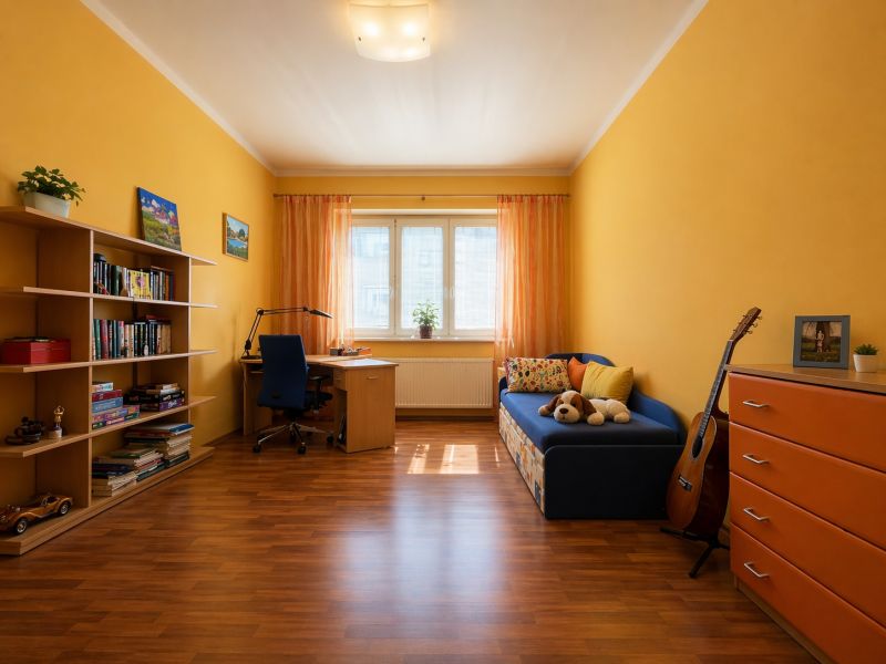 A room with yellow walls, a wooden floor, a blue sofa, and bookshelves.