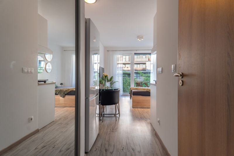 Interior of a 1-room apartment with a wooden decor floor and a large window.