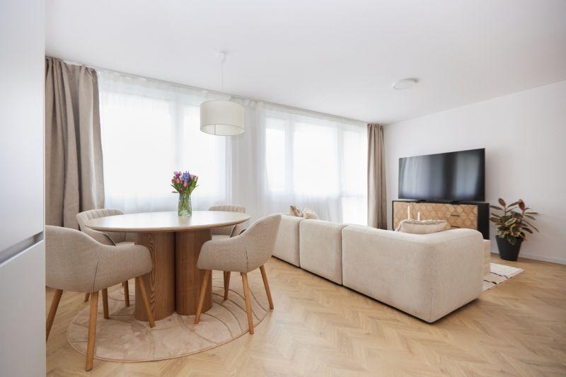 Living room with wood-patterned flooring in a 4-room apartment, seating area and table with flowers.