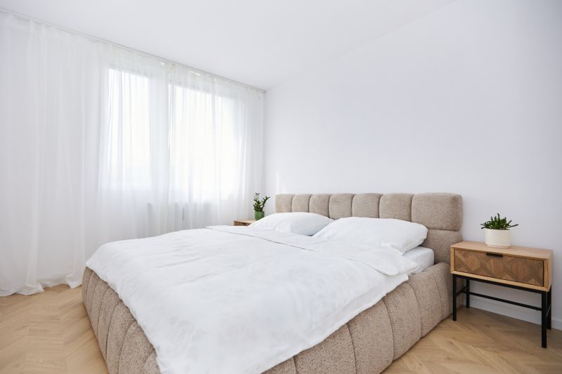 A bedroom with light walls, a bed, and a table in a 4-room apartment, with a wooden decor floor.