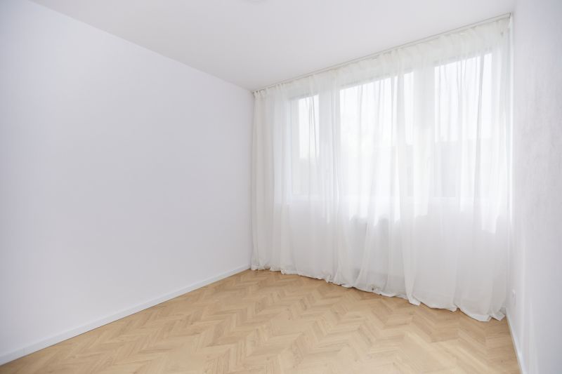 A spacious room with a wooden decor floor and white curtains in a 4-room apartment.