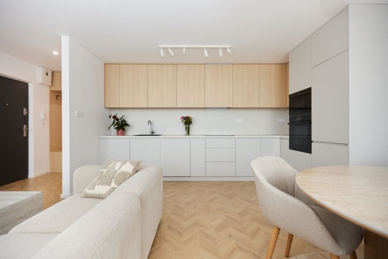 Kitchen in a 4-room apartment, white cabinets, plants, sofa, floor with wooden decor.