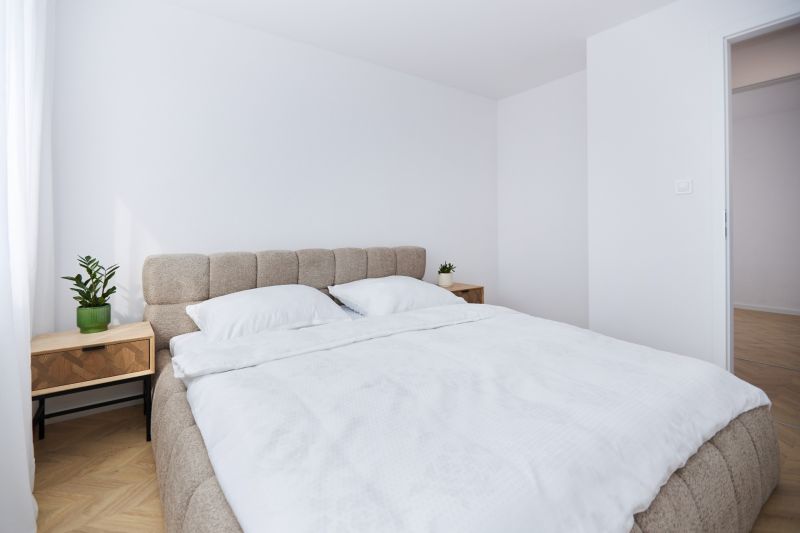 A bright bedroom with a light bed and nightstands in a 4-room apartment.