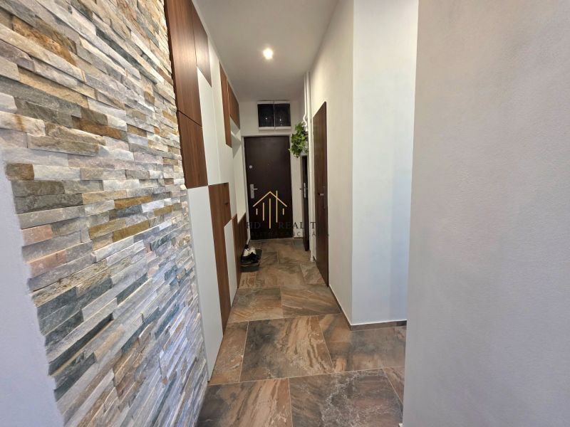 A narrow hallway in a 2-room apartment with a wall of tiles and flooring.