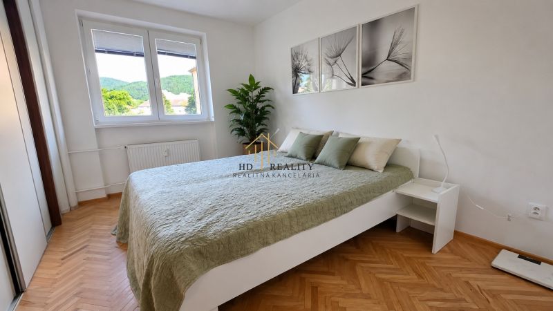A room in a 2-room apartment with a wood-decorated floor and a large window.