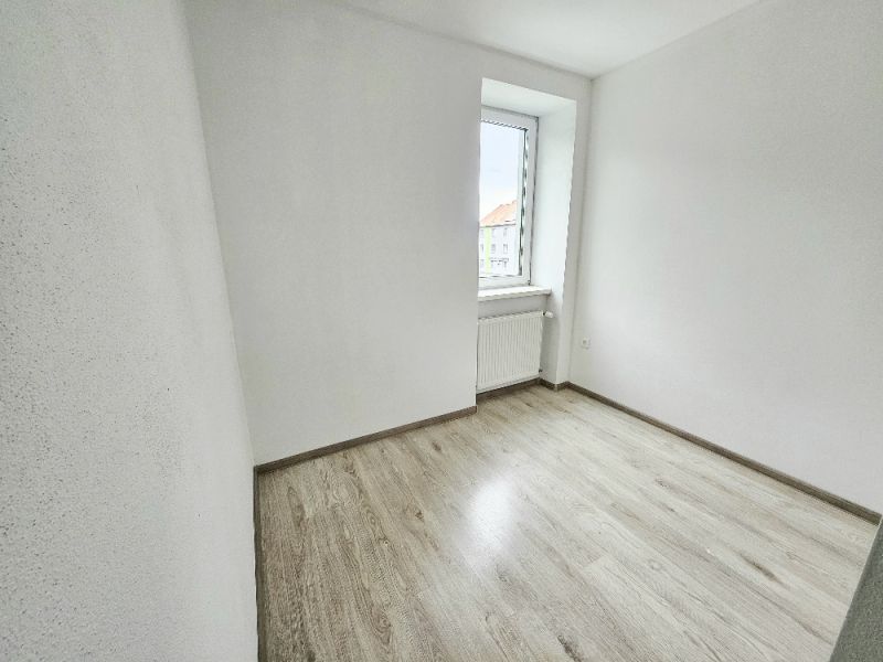 A room in a one-room apartment with a wooden decor floor and a light wall.