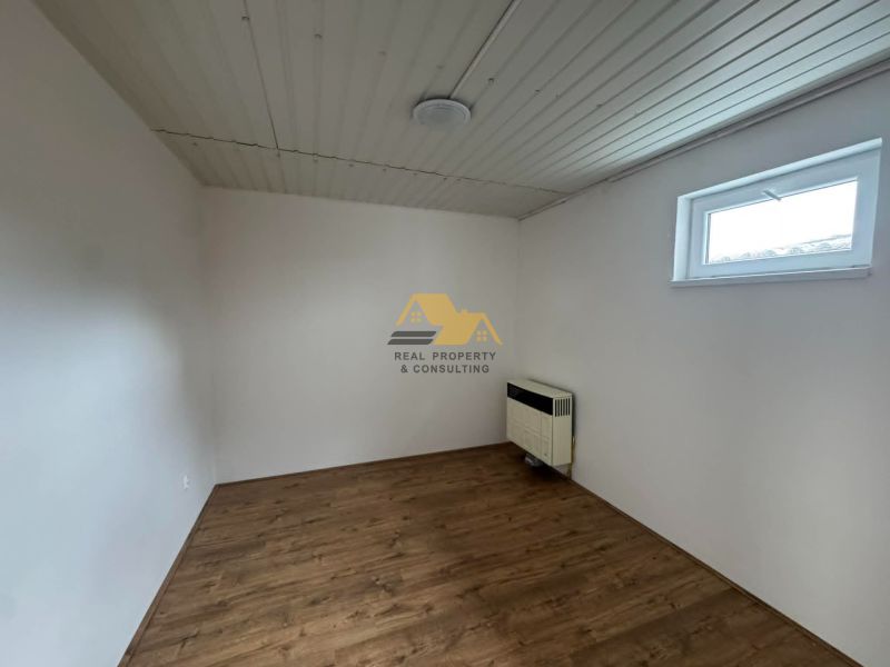 A room with a wooden decor floor and white walls in a 2-room apartment.