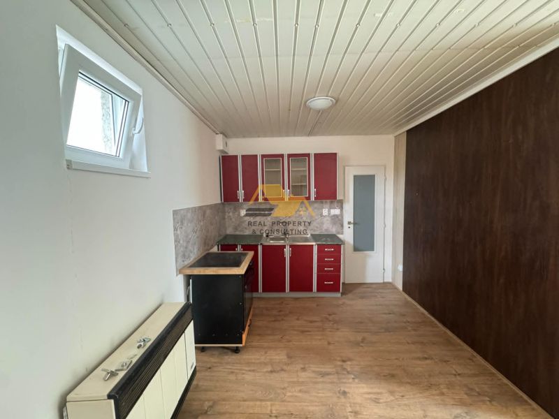 A kitchen unit with red cabinets and a wooden decor floor in a 2-room apartment.