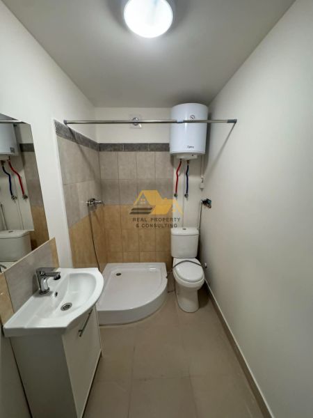 Bathroom in a 2-room apartment with a bathtub, sink, and toilet, light wall tiles.