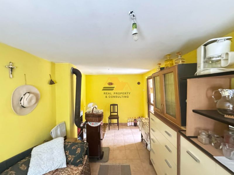 The interior of a cabin with bright yellow walls, a sofa, a wardrobe, and a stove.