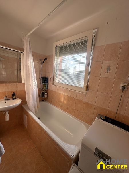 Bathroom in a 3-room apartment with a bathtub, sink, and washing machine, tiles with warm tones.