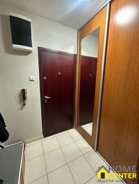 Entrance hall in a 3-room apartment with a mirrored wardrobe and light tiles.