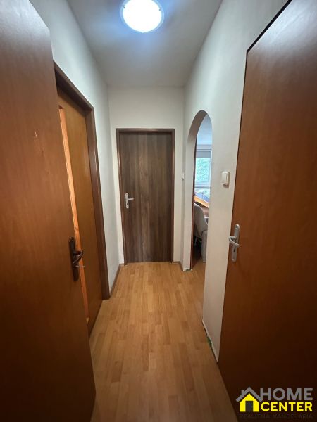 A hallway in a 3-room apartment with a wooden decor floor and doors.
